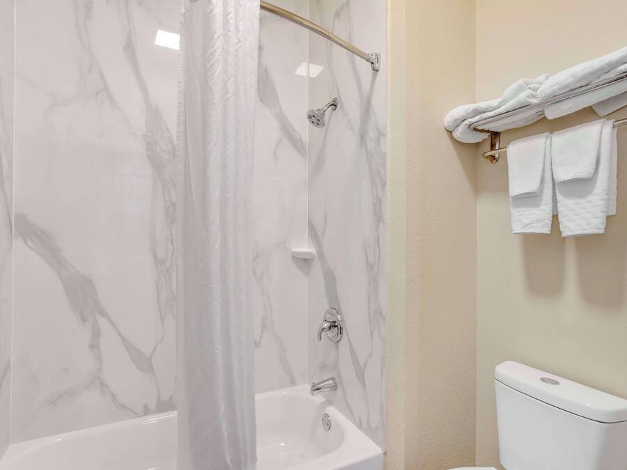 Un baño con cabina de ducha de mármol, bañera blanca y retrete.