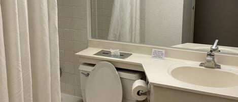 A bathroom with a toilet, sink, and shower curtain.