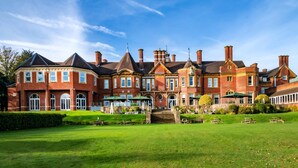 A large, historic building with a symmetrical facade, multiple chimneys, and a well-maintained lawn with outdoor seating. - Moor Hall Hotel, BW Premier Collection (Sutton Coldfield)