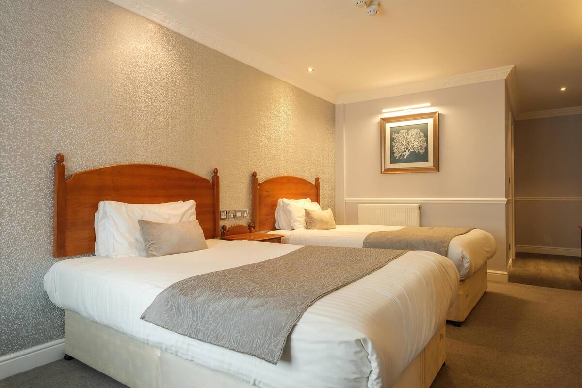 A hotel room with two beds, a framed picture on the wall, and a carpeted floor.