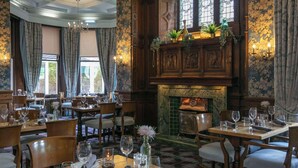 A dining area with wooden tables and chairs, a fireplace, and floral wallpaper. - Moor Hall Hotel, BW Premier Collection (Sutton Coldfield)
