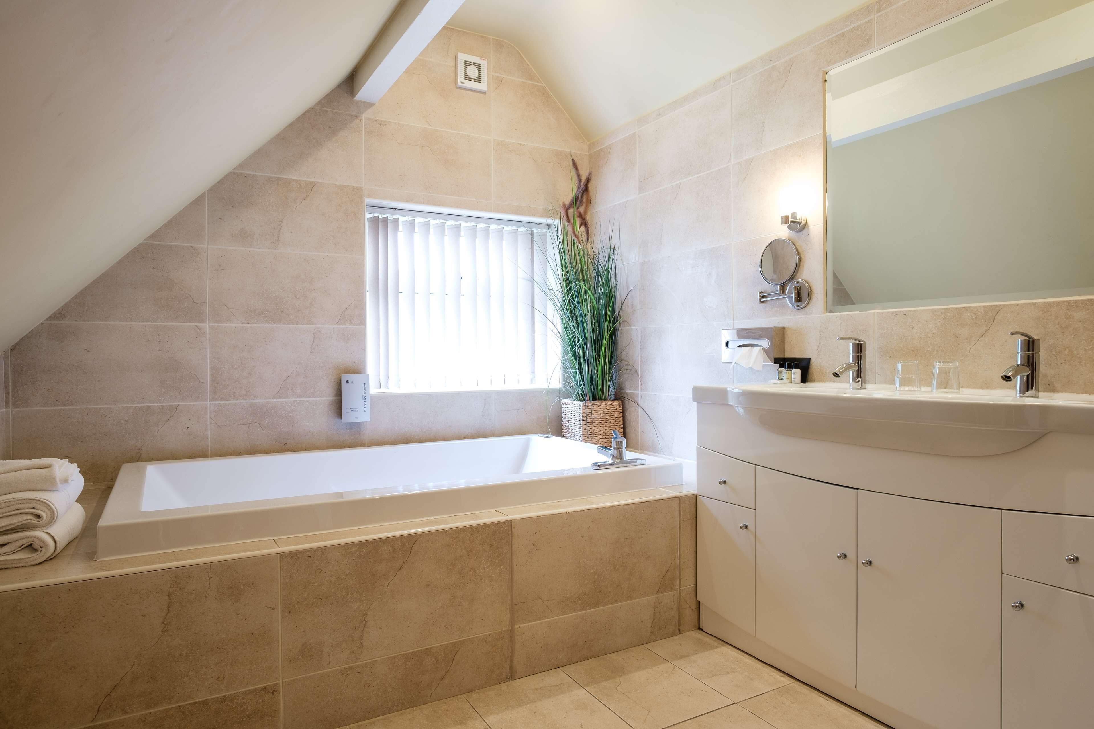 A modern bathroom with a freestanding bathtub, a large mirror, and a vanity with a sink and cabinets.