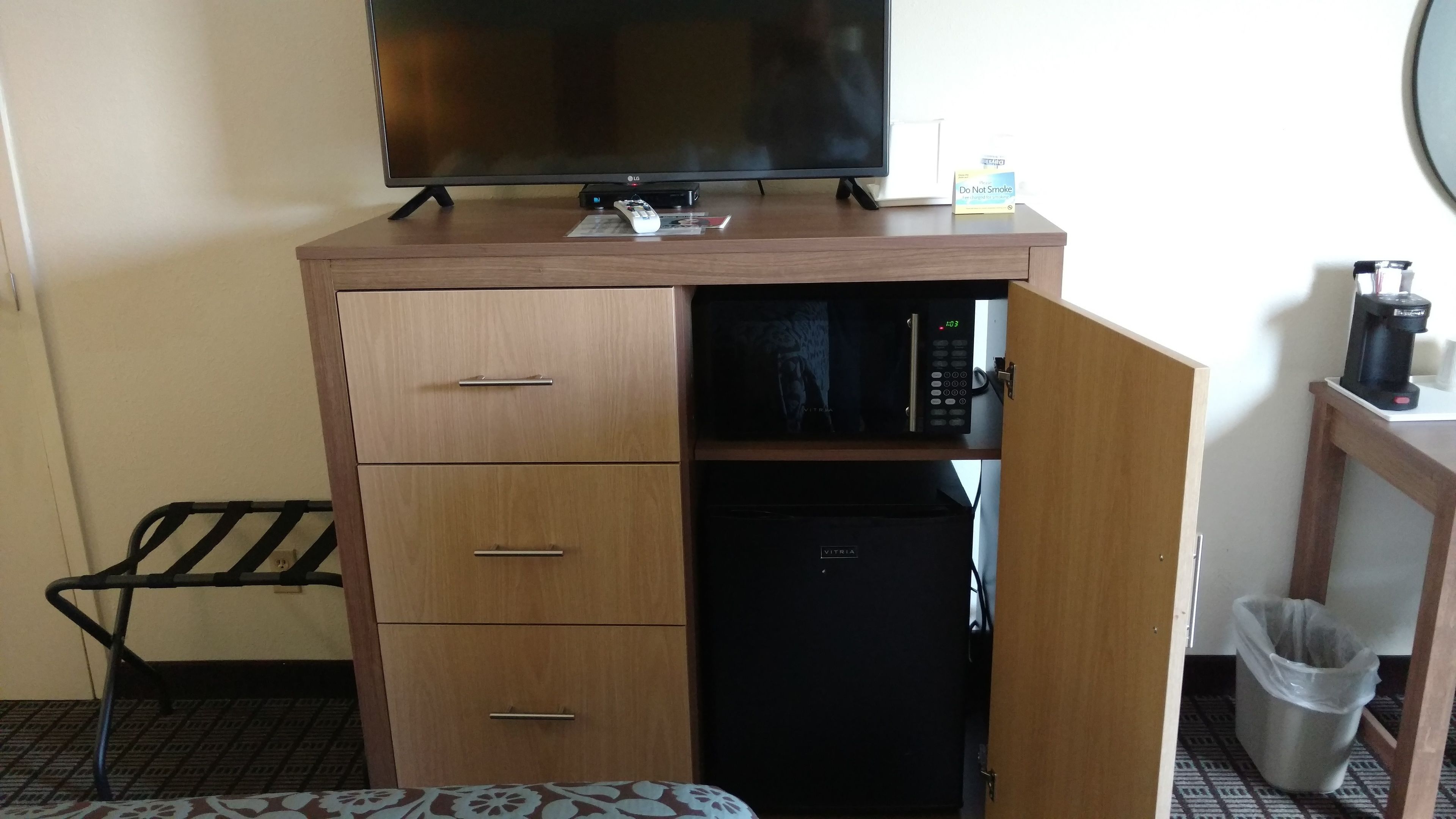 A compact room with a wooden cabinet, a television, a small refrigerator, and a coffee maker.