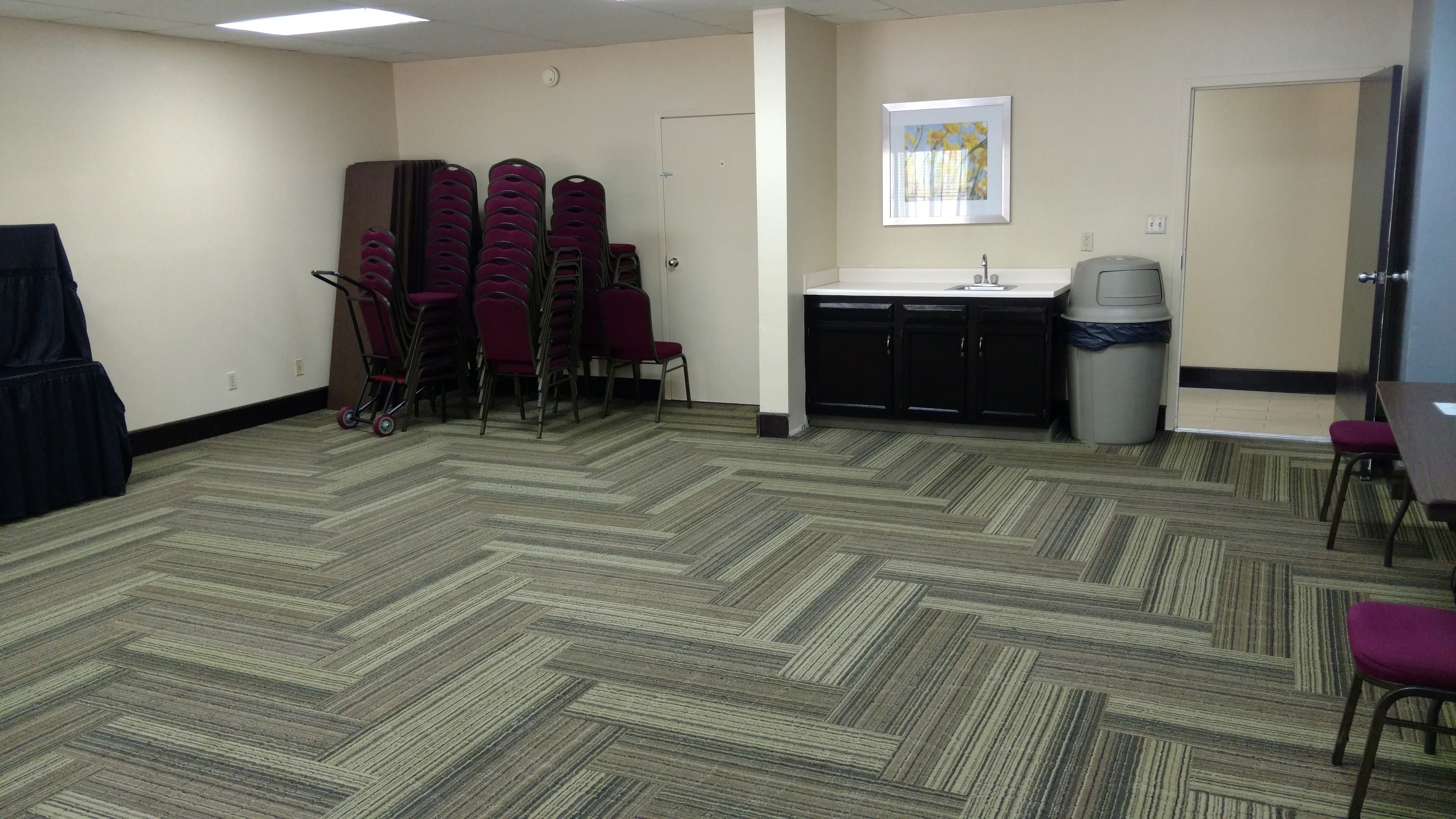 Une salle de conférence dotée d’un sol recouvert de moquette, d’un évier et d’une poubelle.