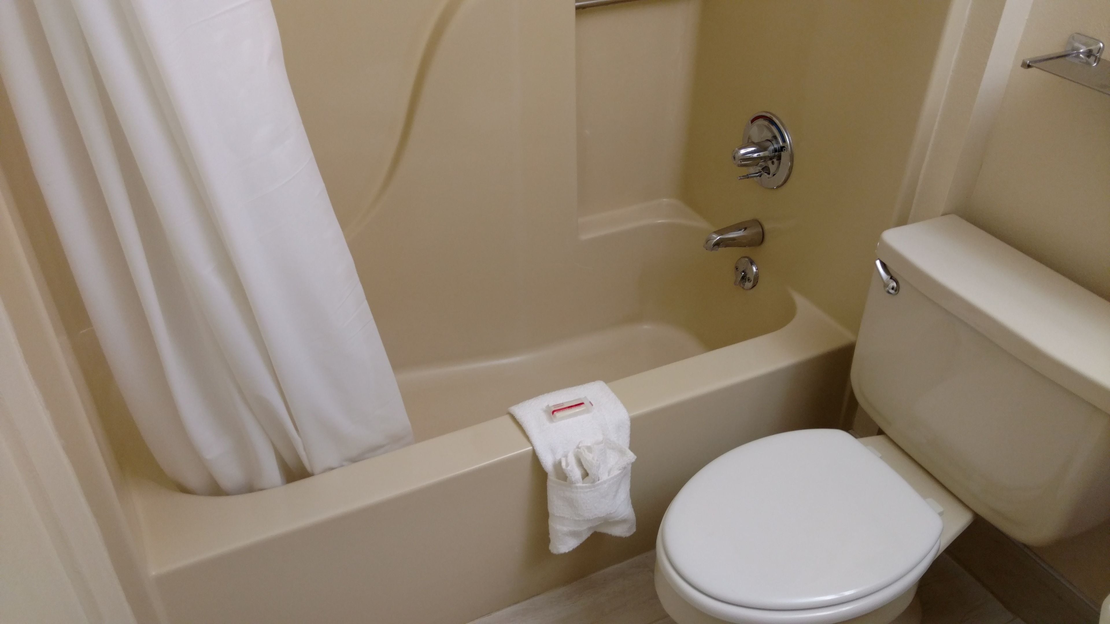 A bathroom with a bathtub, toilet, and a towel hanging on the side.