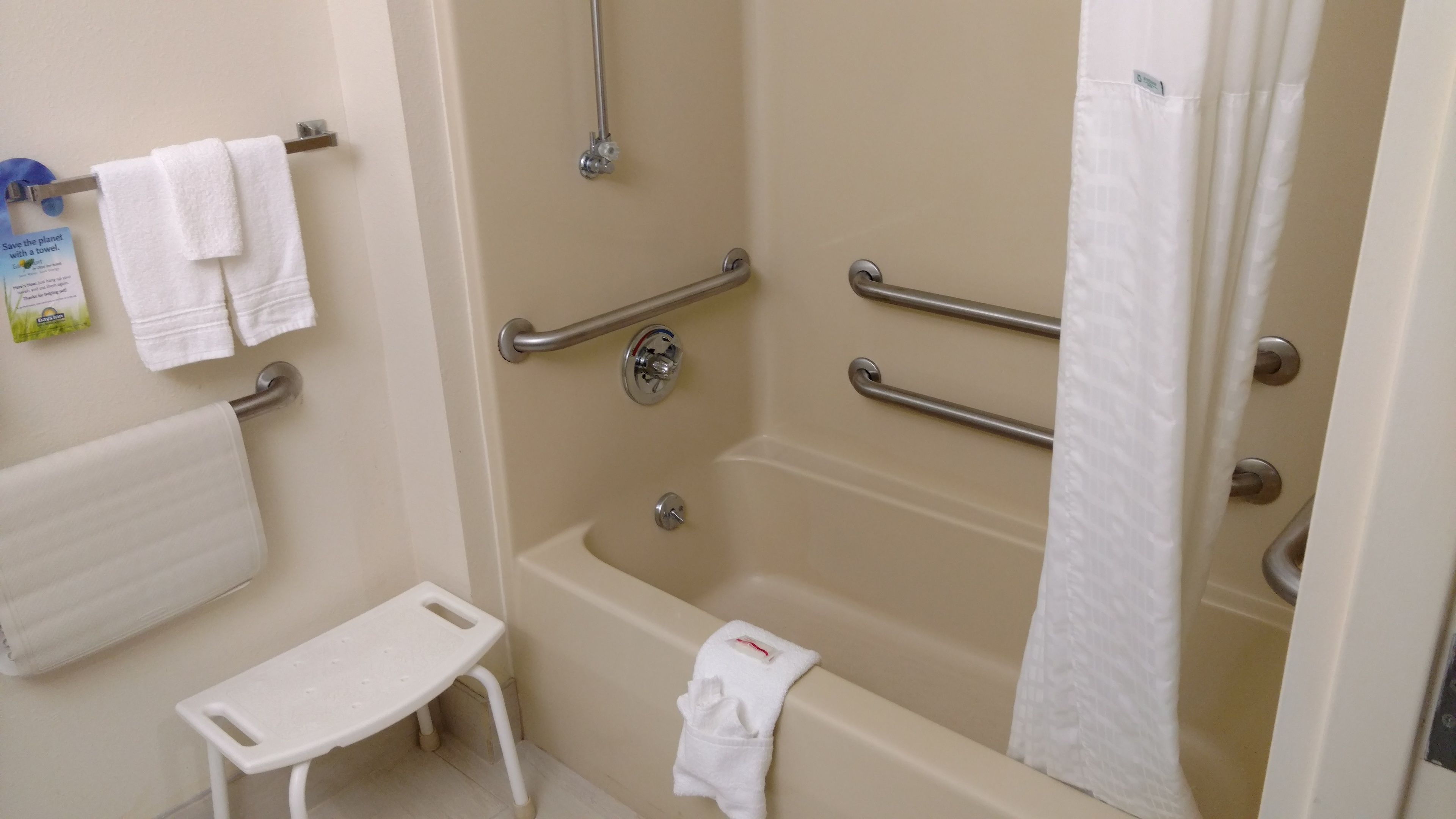 A bathroom with a bathtub, a shower, and a toilet. There are handrails and a grab bar for safety.