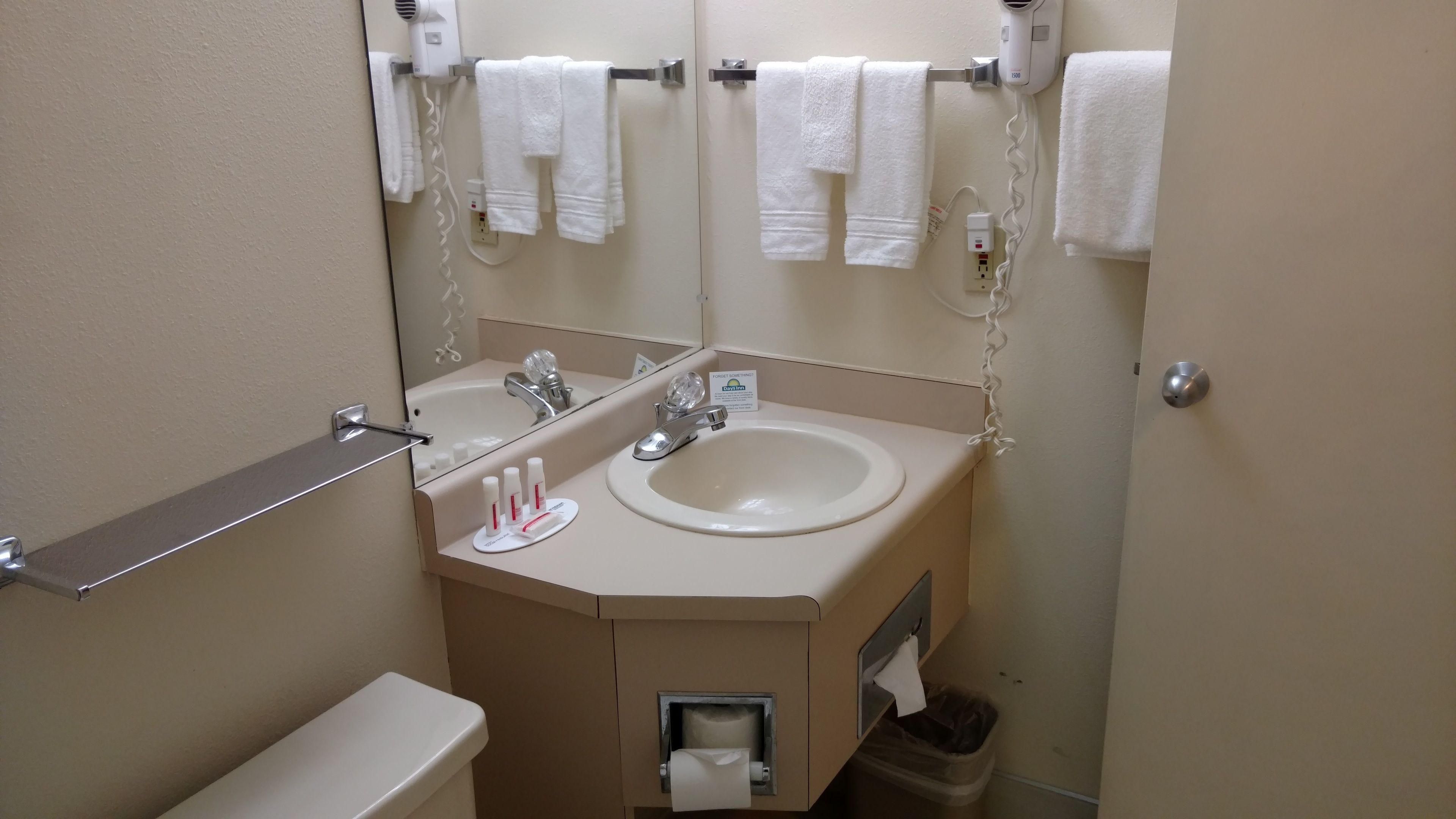 A bathroom with a sink, two mirrors, a towel rack, and a toilet.