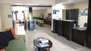 A hotel lobby with a reception desk, seating area, and a dining section. - Days Inn by Wyndham Ashland (Ashland)