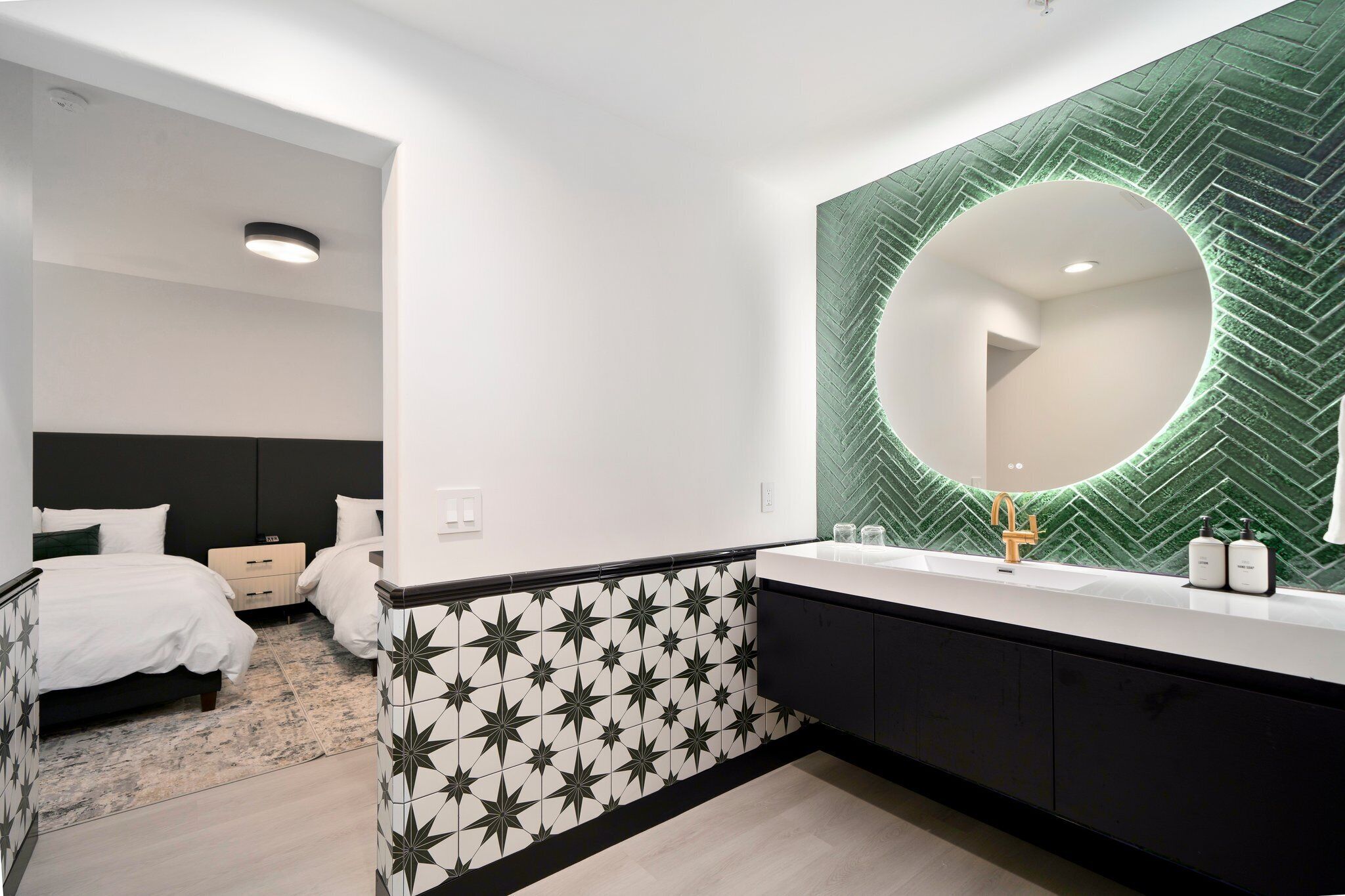 Een moderne badkamer met een grote spiegel, een zwart-wit behang en een witte wastafel.