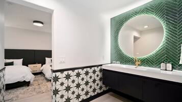 Een moderne badkamer met een grote spiegel, een zwart-wit behang en een witte wastafel.