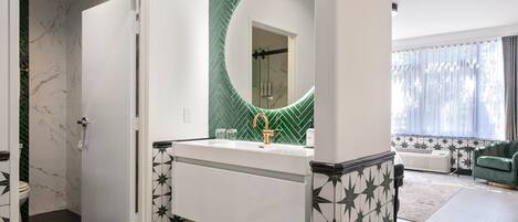 A modern bathroom with a white vanity, a green herringbone-patterned wall, and a large mirror.