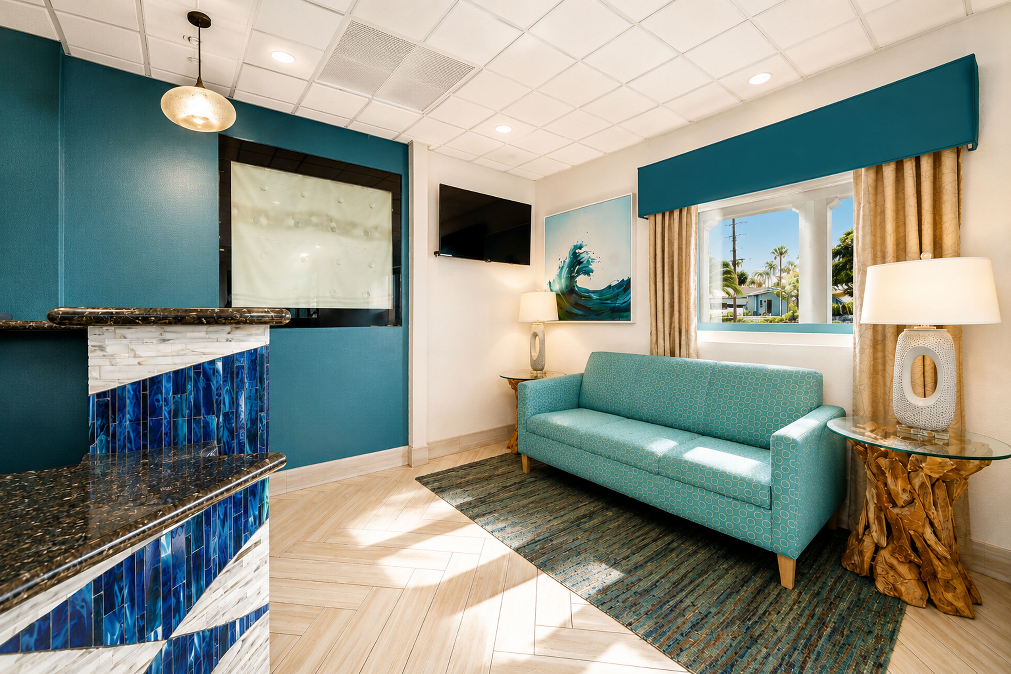 Een moderne woonkamer met een blauwe bank, een glazen salontafel, een open haard, een flatscreen televisie en uitzicht op het landschap.