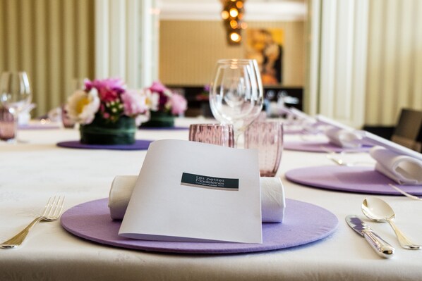 A table set with purple placemats, a menu, and silverware.