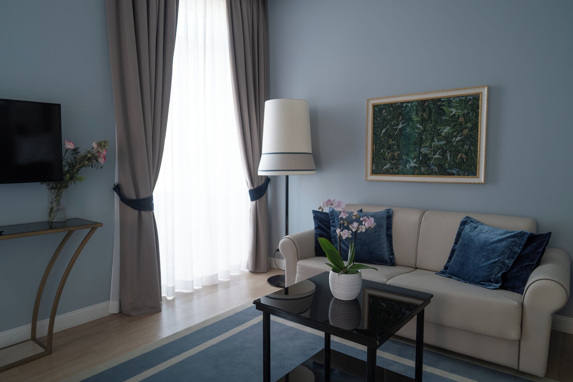A modern living room with a sofa, a coffee table, a TV, a lamp, and a painting on the wall.
