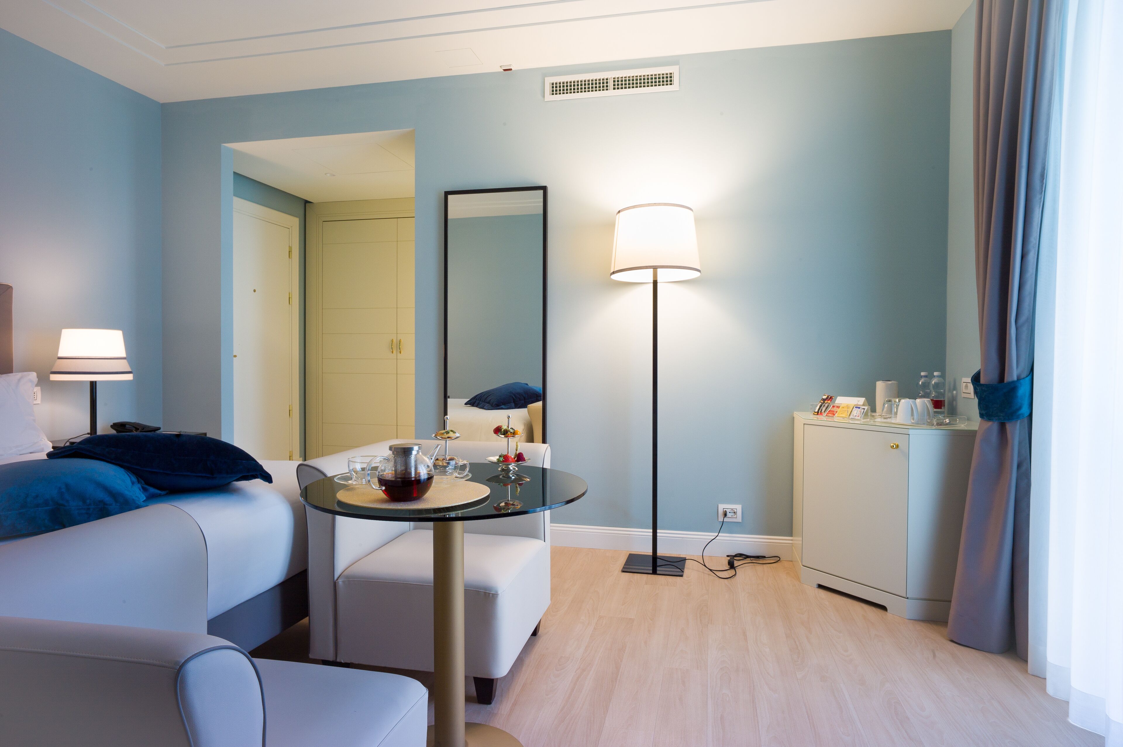 Ein Hotelzimmer mit einem Bett, einem kleinen Tisch mit Lampe, einem Spiegel und einem Schrank.