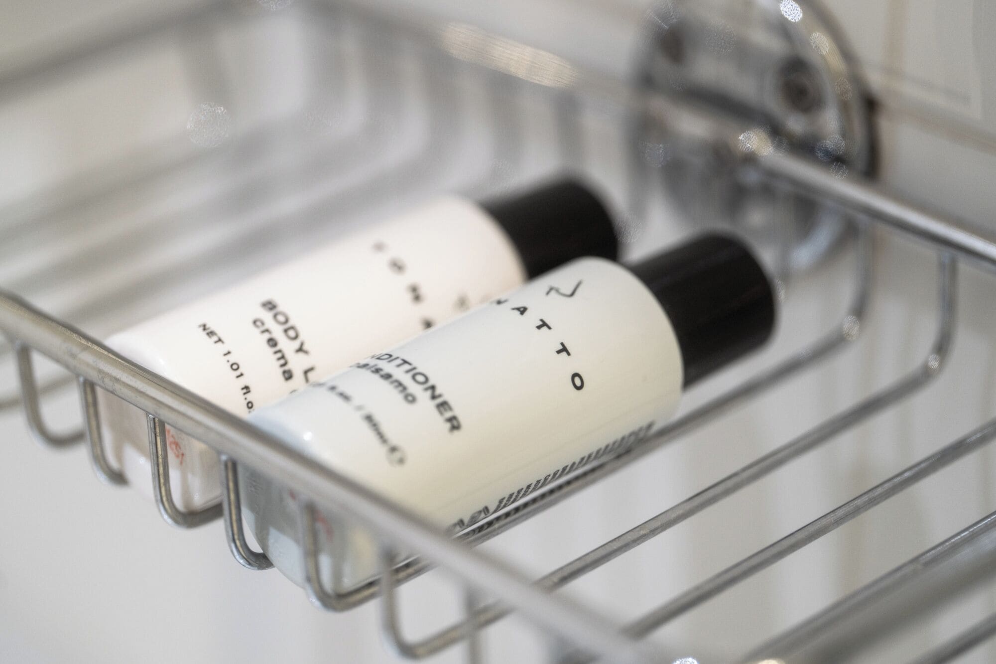 A bathroom shelf with two bottles of body lotion and a black bottle.