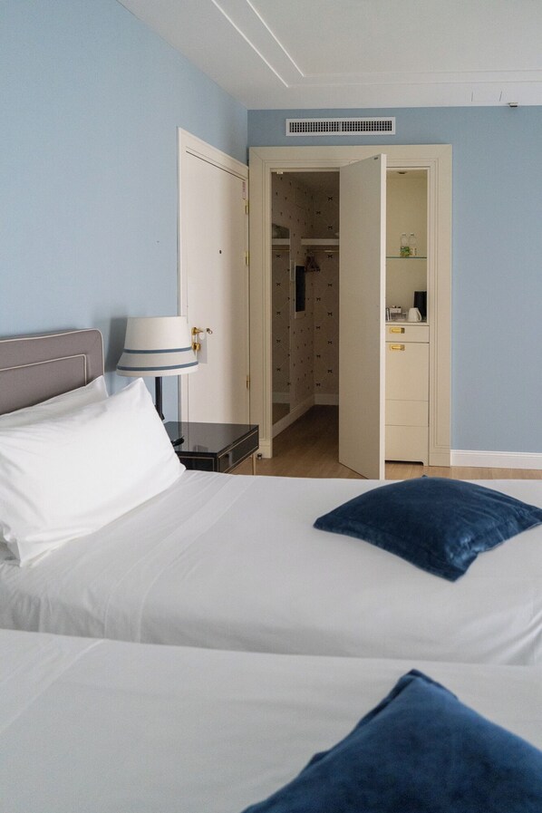 A hotel room with a bed, a bedside lamp, a wardrobe, and a bathroom visible through an open door.