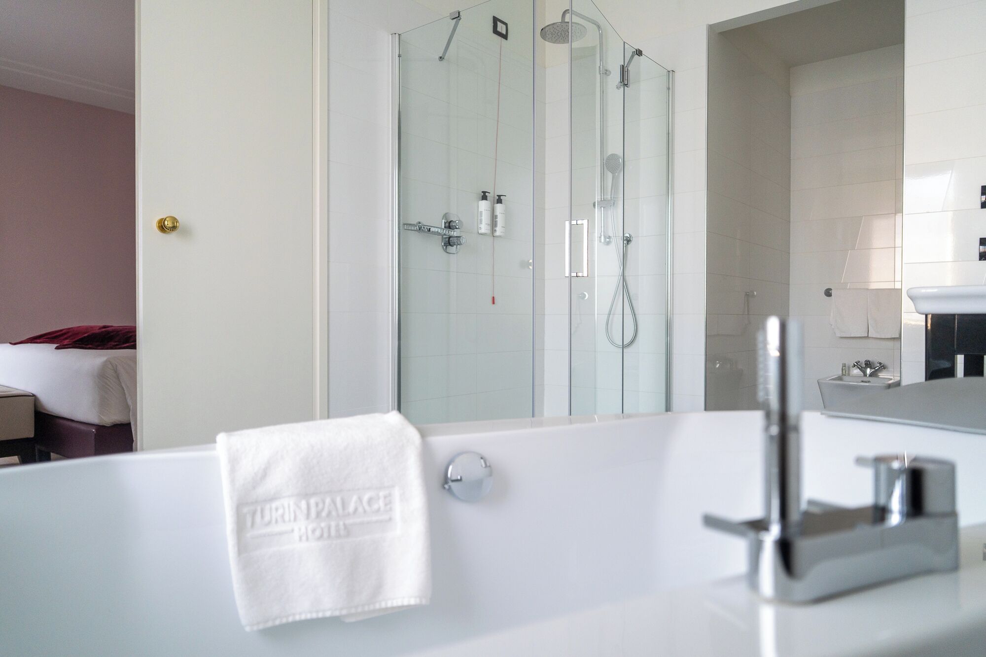 A modern bathroom with a glass-enclosed shower, a white bathtub, and a mirror reflecting the room.