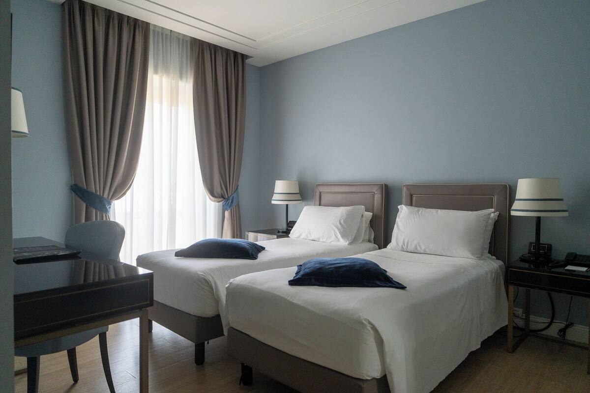 Une chambre d’hôtel avec deux lits, un bureau et une chaise.