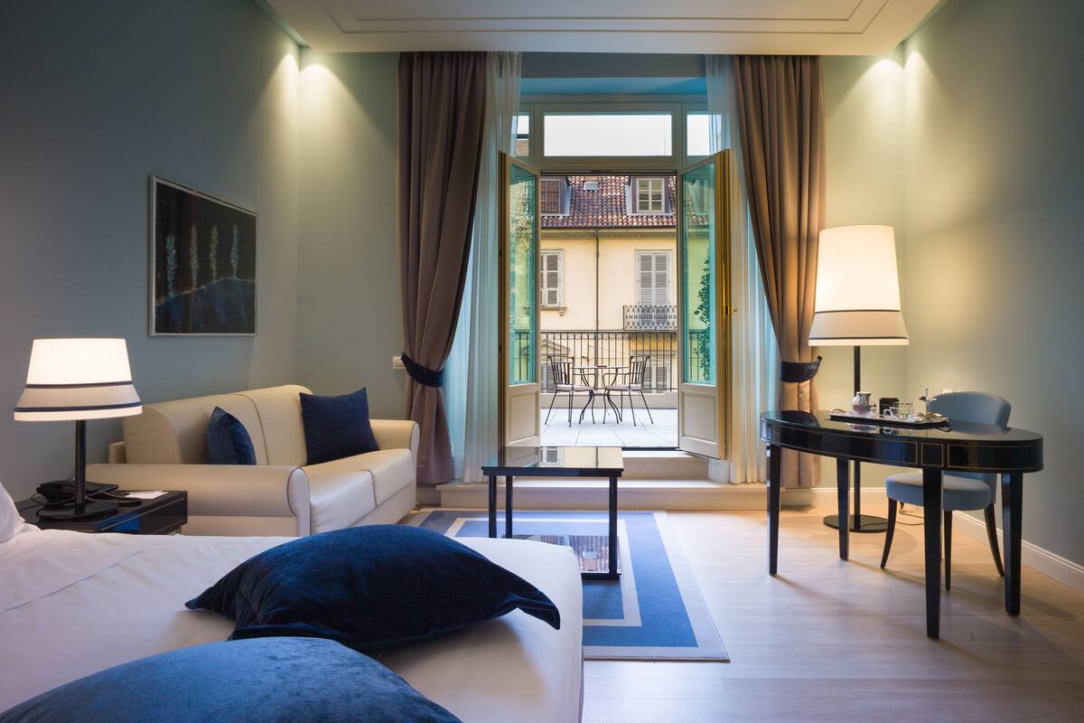 Une chambre d’hôtel comprenant un lit, un canapé, une table à manger et un balcon avec vue sur les bâtiments.