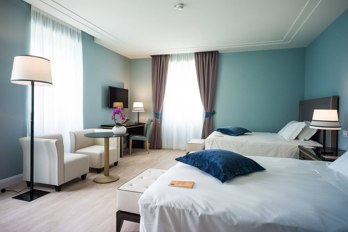 Une chambre d’hôtel avec deux lits, un bureau, une chaise et une petite table.