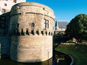 A historic stone tower with a cylindrical shape, featuring a series of windows and a small balcony.