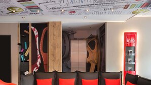 Un espace détente moderne avec un ensemble de canapés, une petite table et un panneau néon indiquant « informations ».