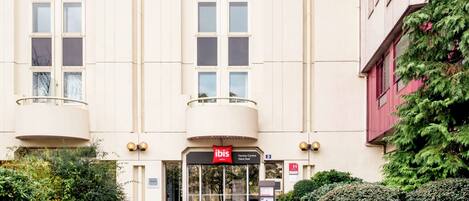 A hotel entrance with a glass door, a red sign, and a small sign indicating the entrance number.