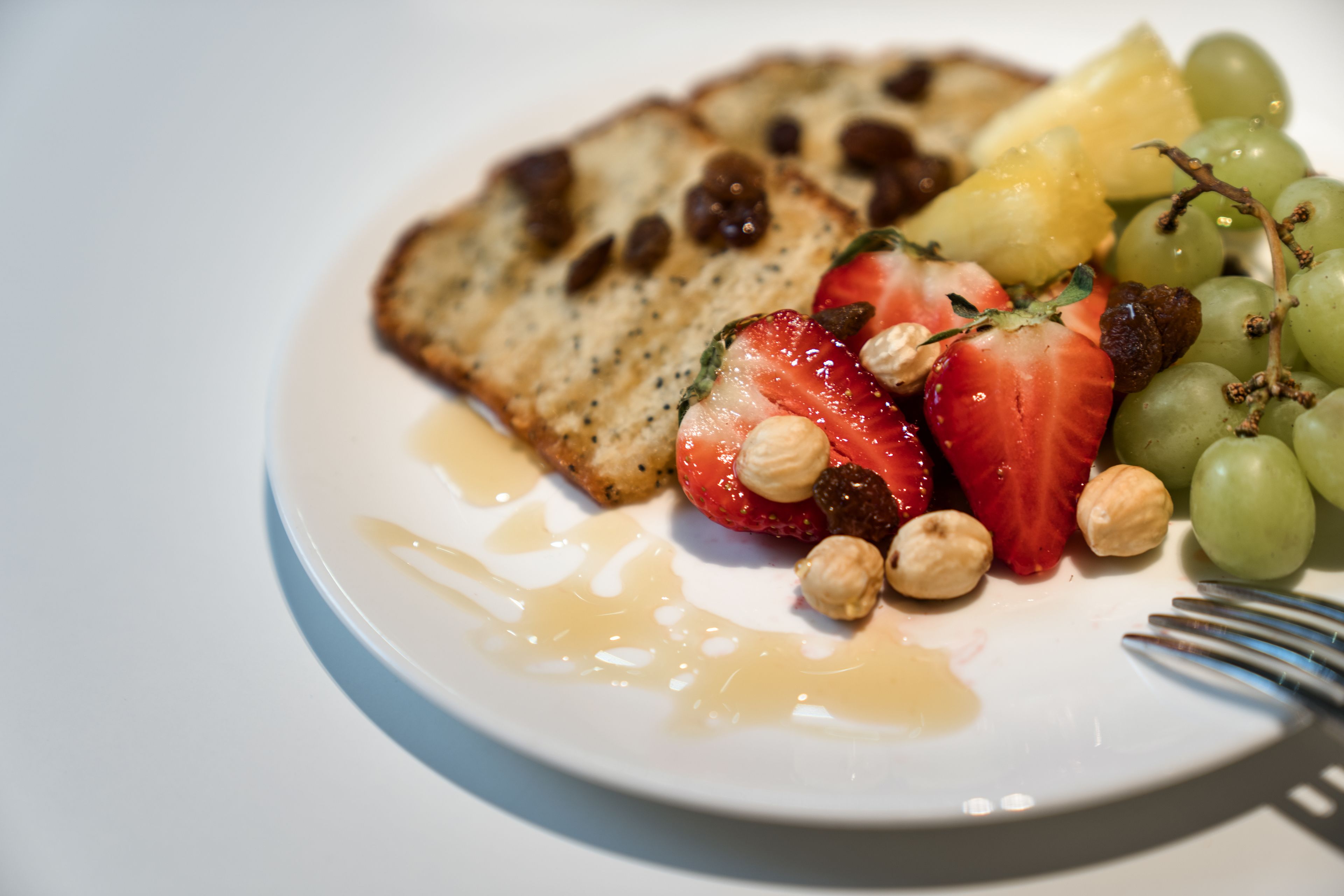 A plate with toast, strawberries, grapes, and nuts.
