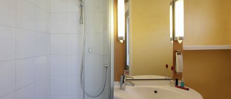 Un baño con ducha, lavabo y espejo.