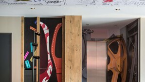 Une pièce moderne avec un séparateur en bois, un grand objet rouge et blanc, un meuble métallique et une chaise rouge.