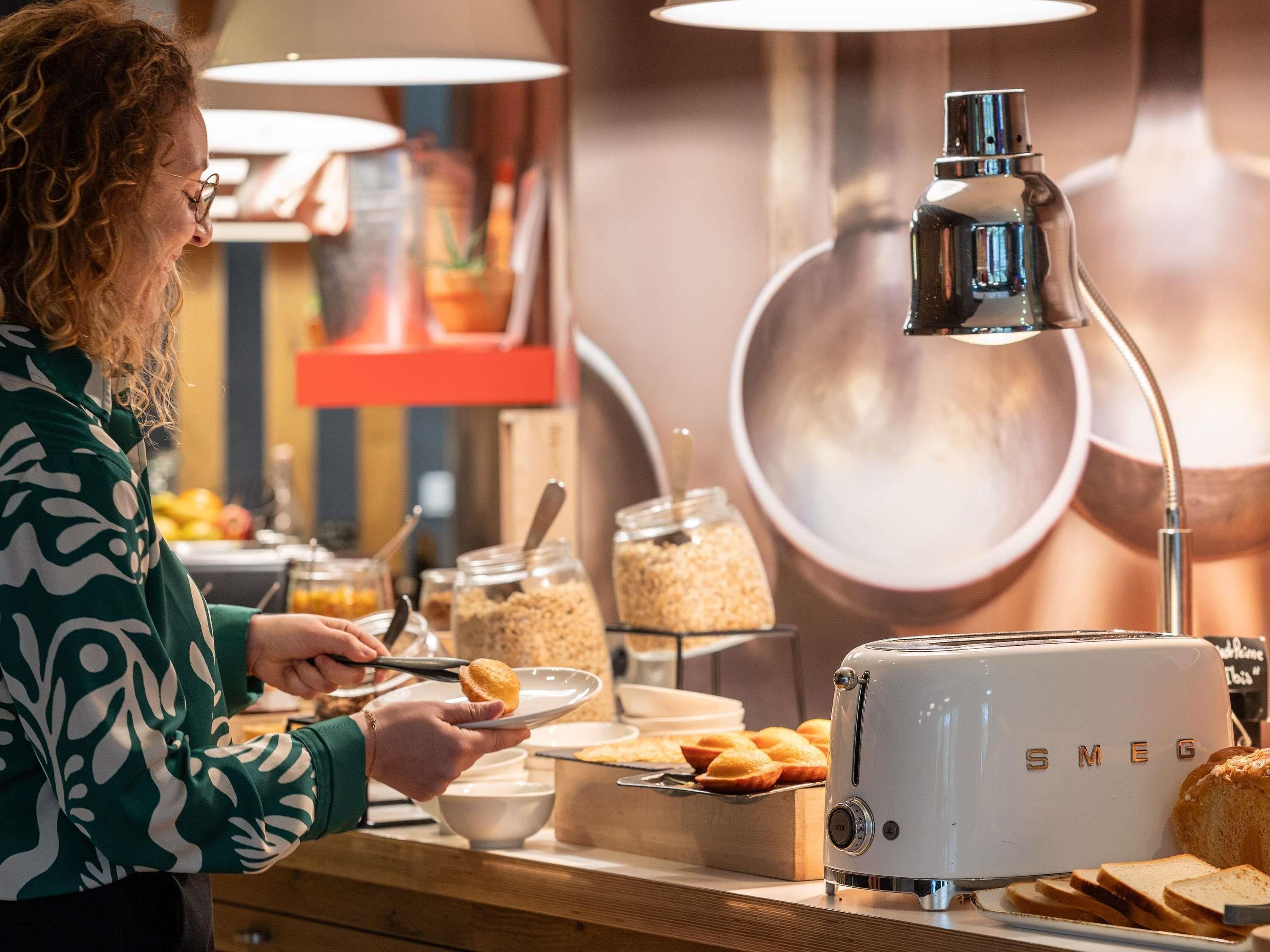 A buffet setup with a toaster, bowls, and jars of condiments.