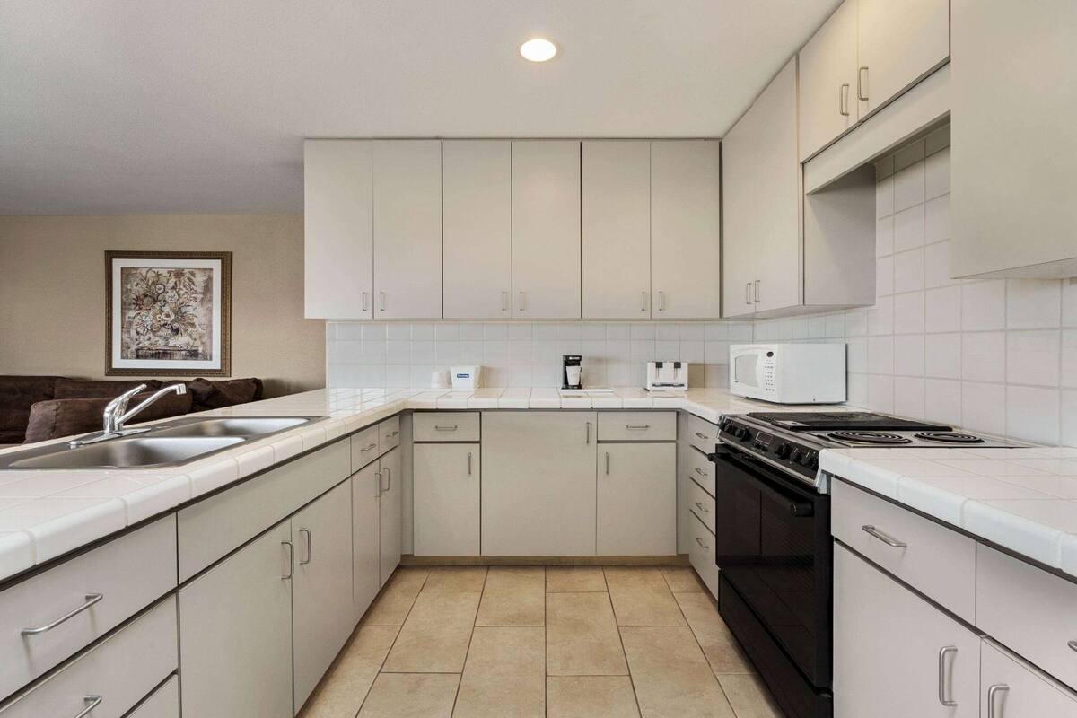 A compact kitchen with white cabinets, a black stove, and a microwave.