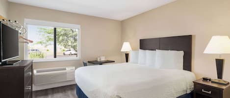 A hotel room with a large bed, bedside lamps, a TV, and a window with a view of the outside.