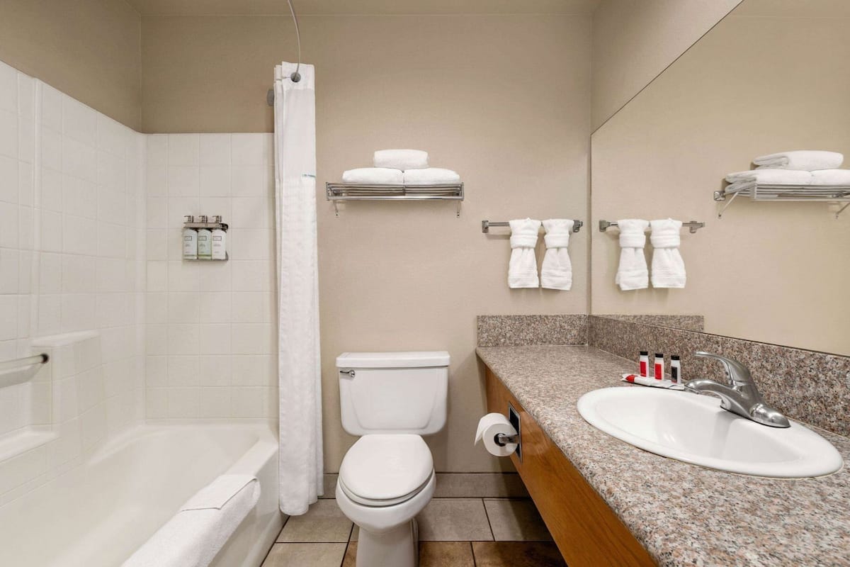A bathroom with a bathtub, toilet, sink, and towel racks.