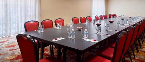 A conference room with a long table, red chairs, water bottles, and glasses.