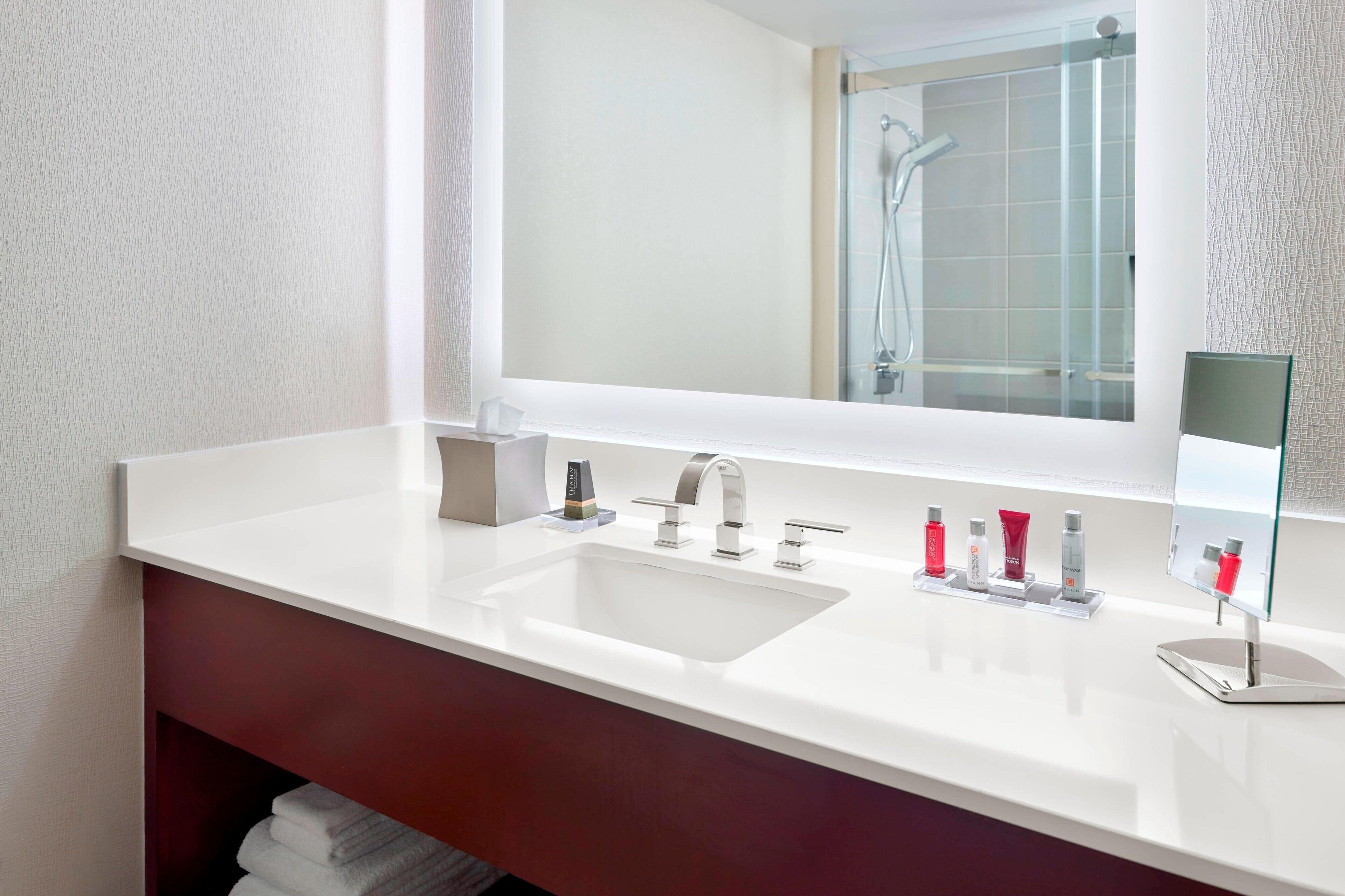 A modern bathroom with a white sink, a large mirror, and a glass shower enclosure.