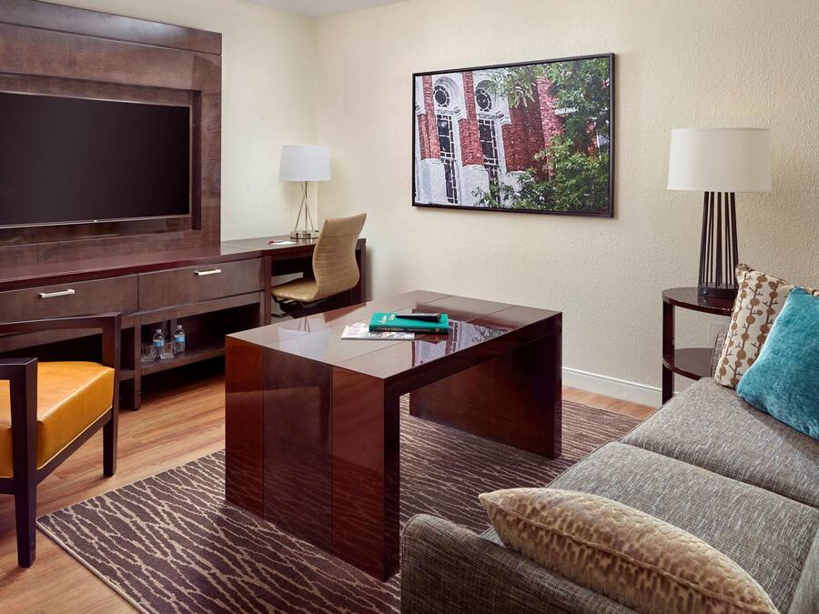 A living room with a flat-screen TV, a sofa, a coffee table, and a chair.