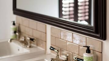 Un baño con un espejo grande, dos lavamanos y una botella de champú.
