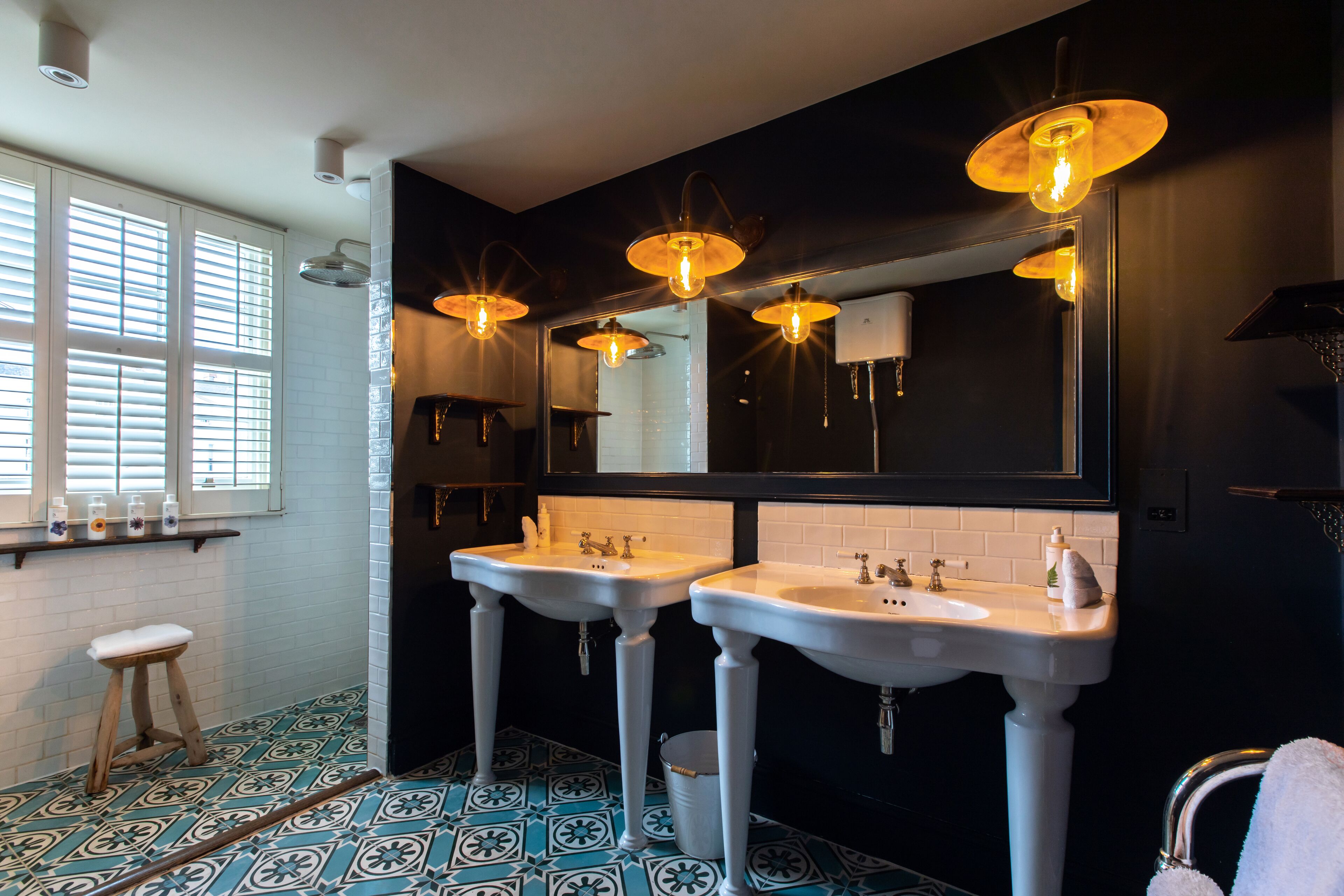 A bathroom with two sinks, a large mirror, and a window with blinds.