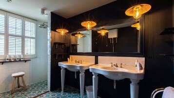 A bathroom with two sinks, a large mirror, and a window with blinds.