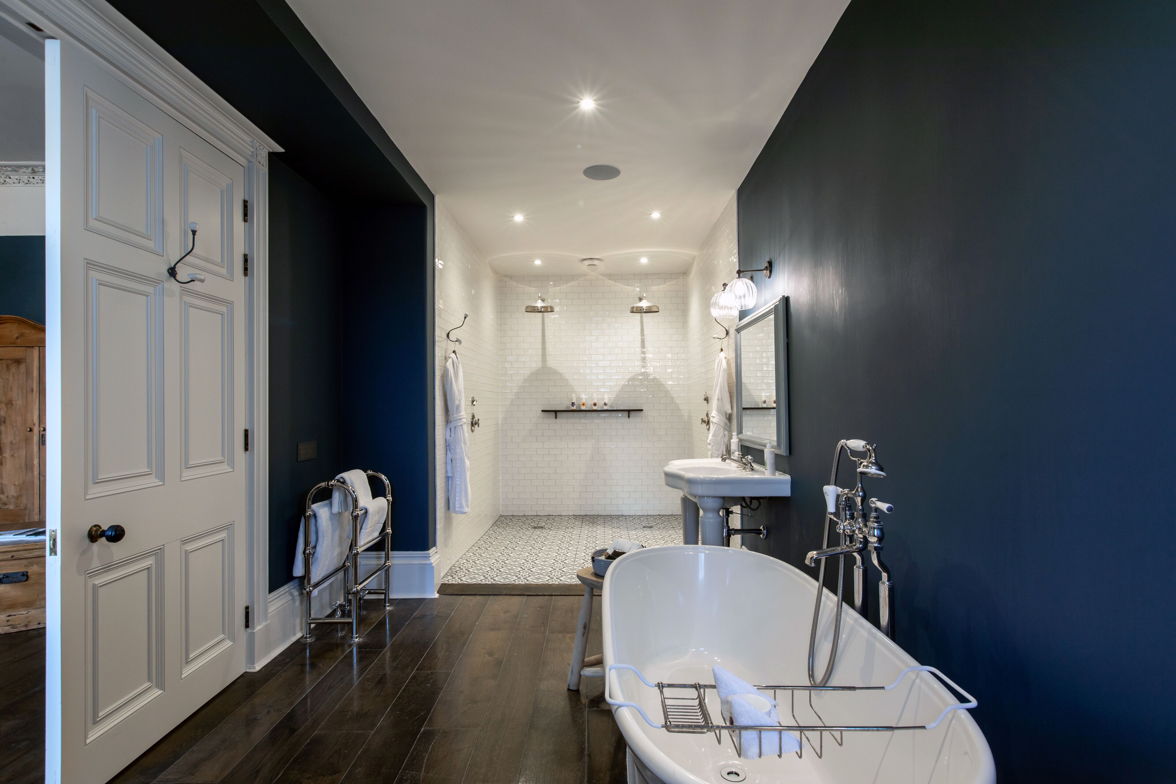 A modern bathroom with a freestanding bathtub, a vanity with a mirror, and a shower area.