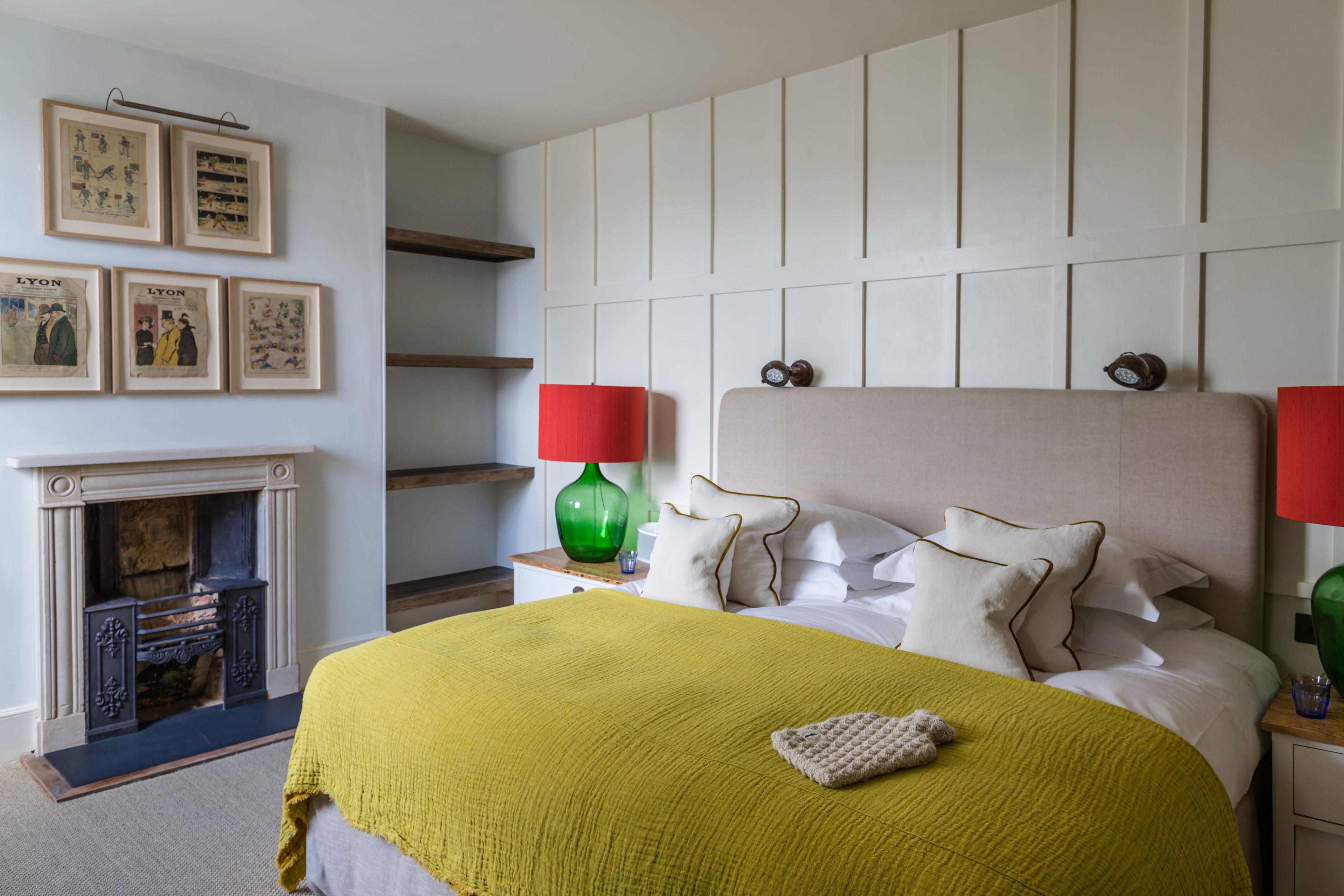 Une chambre à coucher avec un lit, une cheminée et des tableaux encadrés accrochés au mur.