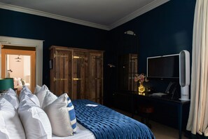 A bedroom with a large bed, wooden wardrobe, desk with a computer, and a television. - No 38 The Park (Cheltenham)