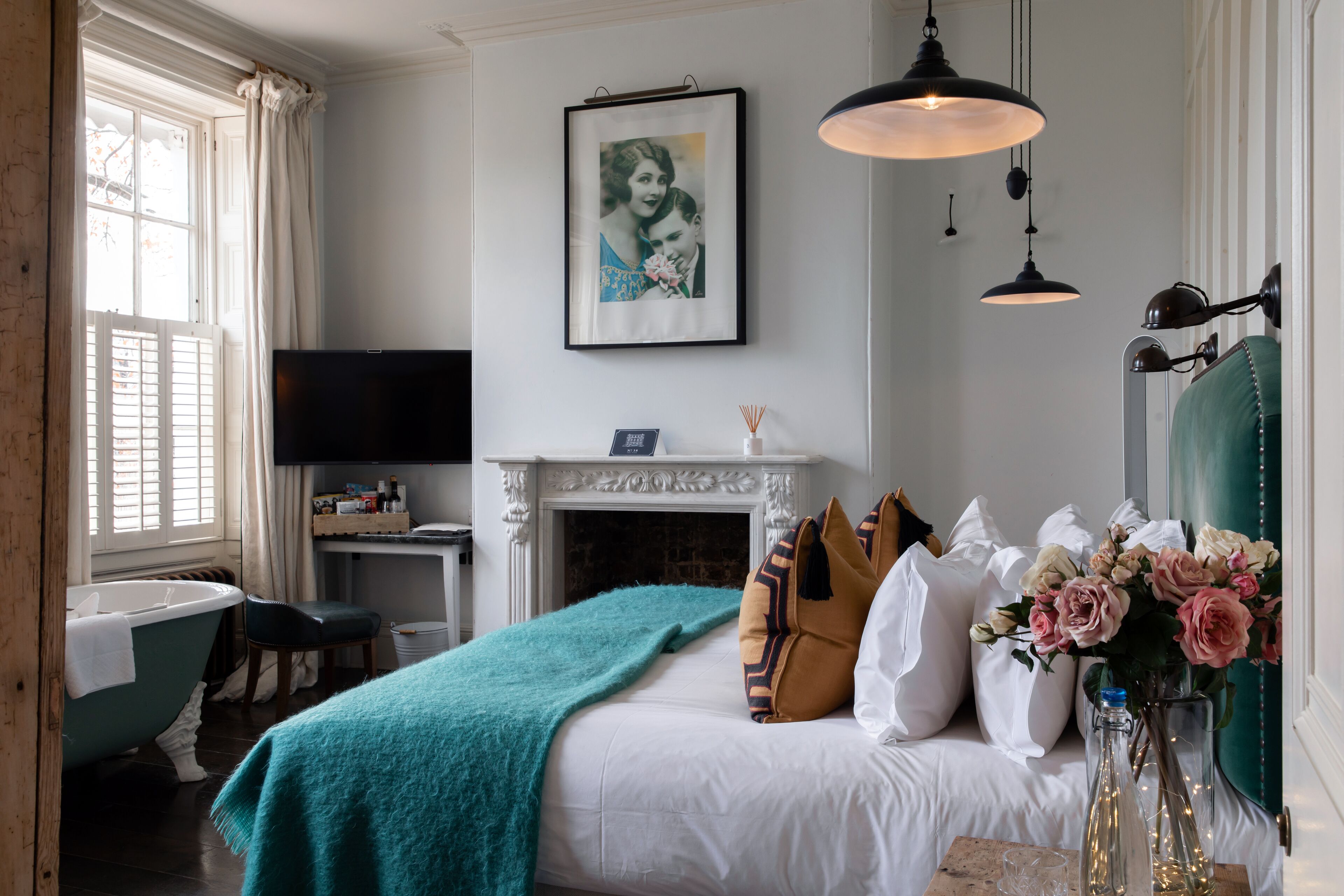 Une chambre à coucher avec un lit, une cheminée, une télévision et une fenêtre avec des rideaux.