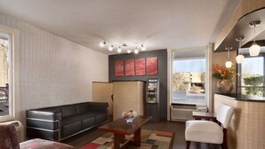 Ein Wohnzimmer mit einem schwarzen Ledersofa, einem Holztisch und einem gemusterten Teppich.