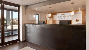 Ein Empfangsbereich mit einem Schild für Baymont Inn & Suites, einem Glastür-Eingang und Pendelleuchten.