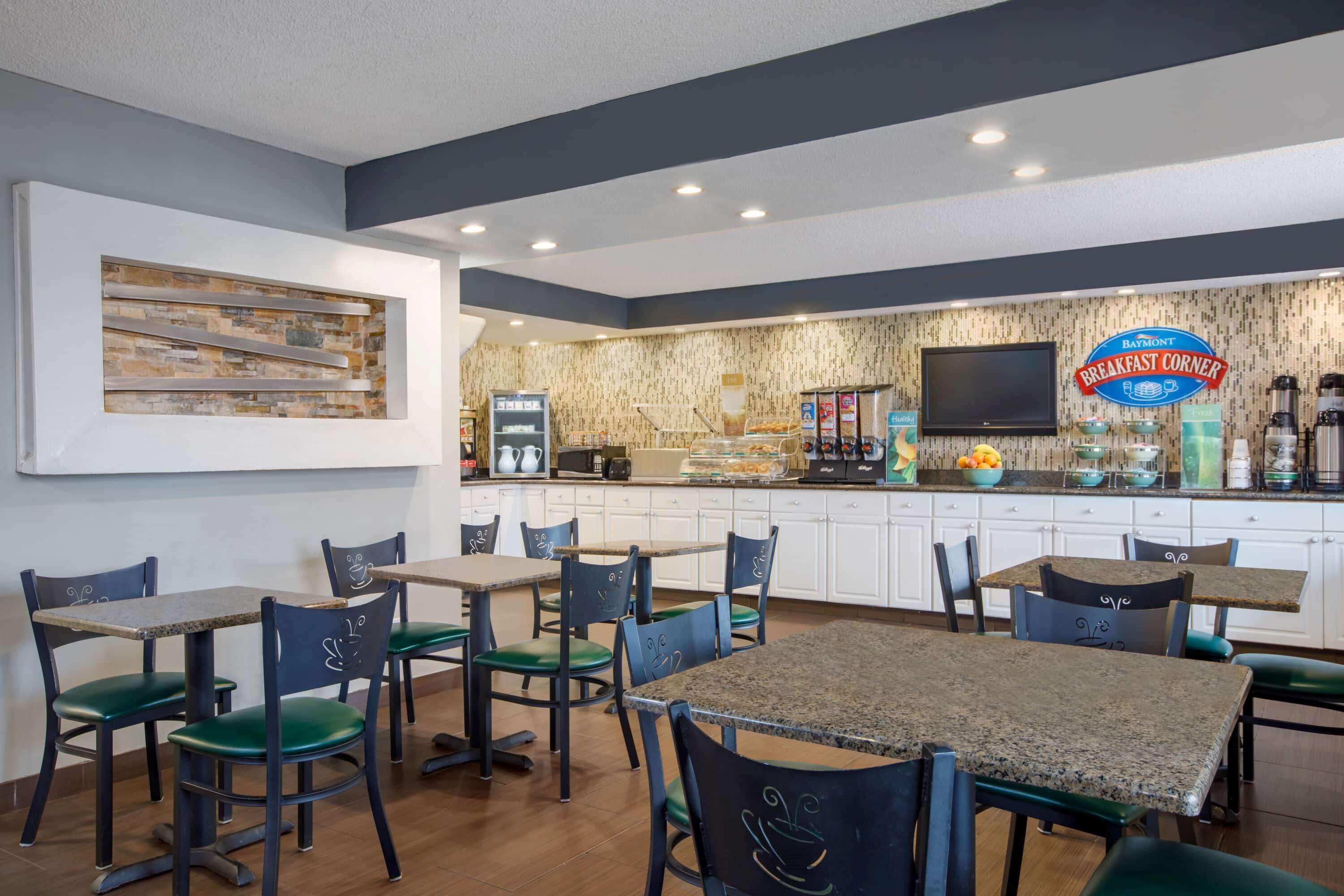 Un comedor con mesas y sillas, una estación de café y un televisor en la pared.