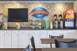 Een ontbijtruimte met een Baymont Breakfast Corner bord, een fruitschaal, een sapautomaat en een koffieapparaat.