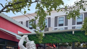 Une statue d’un ange se trouve dans une cour, avec des sièges à l’extérieur et un bâtiment en arrière-plan.